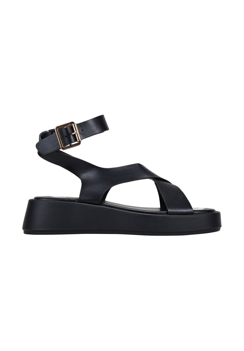 Black platform sandal featuring adjustable ankle strap, crossover straps, smooth leather material, and a chunky, textured sole.