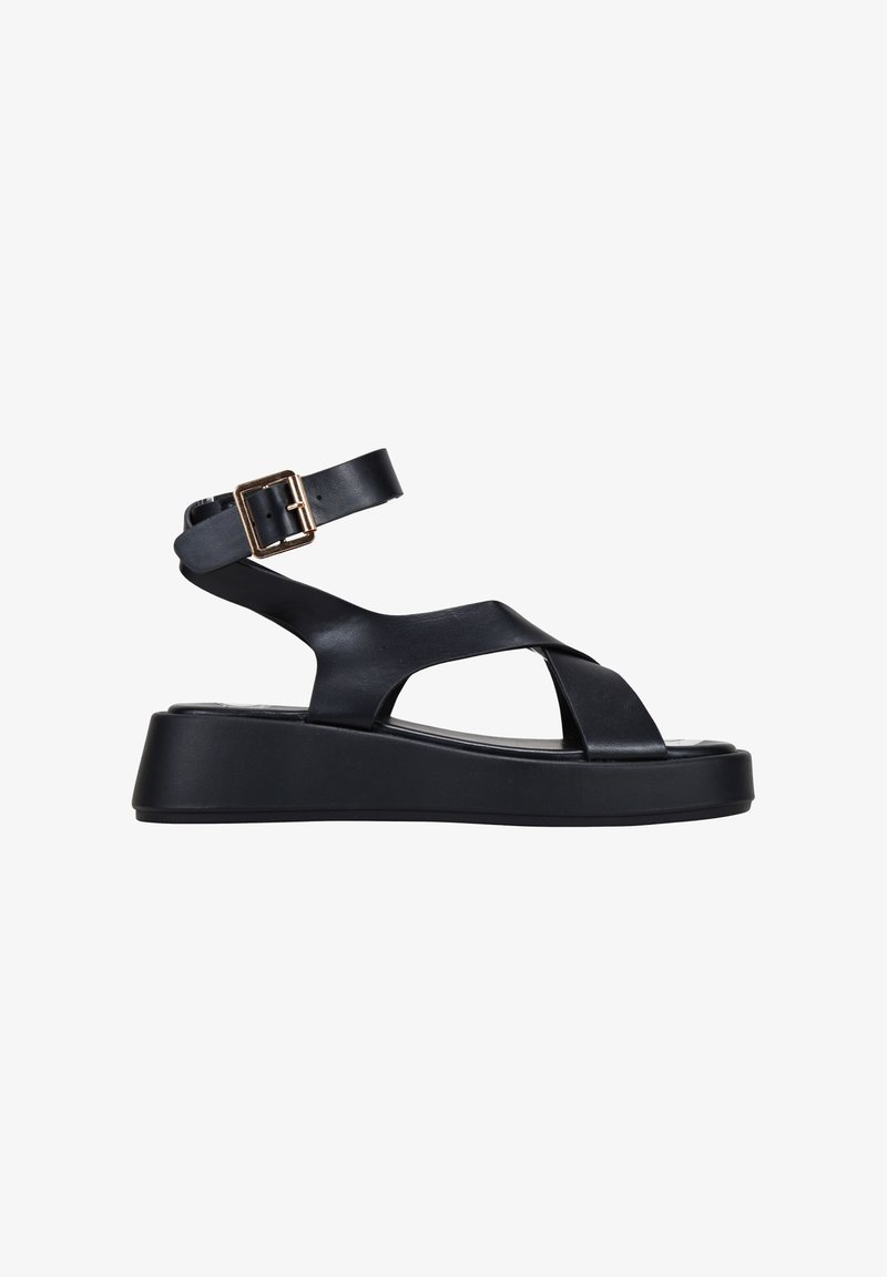 Black platform sandal featuring adjustable ankle strap, crossover straps, smooth leather material, and a chunky, textured sole.