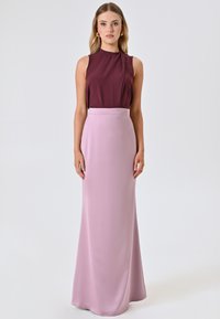 Ärmelloses burgunderfarbenes Top, kombiniert mit einem langen, hellrosa Satinrock. Der Rock hat eine glatte Textur, reicht bis zum Boden und hat eine taillierte Passform.