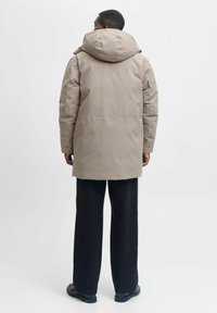 Bežna parka jakna z veliko kapuco, s pravim krojem, dolgimi rokavi in gladkim materialom. V kombinaciji s črnimi širokimi hlačami.