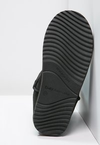 Sola della scarpa nera impermeabile con texture scanalata e marchio "EMU Australia". Design sagomato per una presa e durata migliorate.