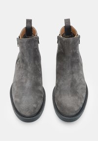 Stivaletti alla caviglia in suede grigio con una texture liscia, punte arrotondate, cerniere laterali e linguette per facilitarne l'indossare. Suole in gomma nera per una buona aderenza.