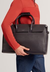 Schwarze Lederaktentasche, rechteckige Form, strukturiertes Design, doppelte Griffe, Logodetail auf der Vorderseite, glatte Textur, minimale Beschläge.