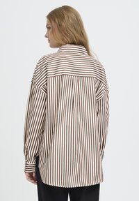 Oversized stribet skjorte i brun og creme, med krave, knapmanchetter og en plissé bagpå for ekstra detalje.