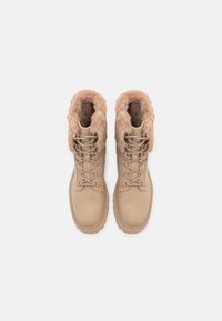 Bottes en daim couleur sable avec un col moelleux, un avant à lacets, et une semelle en caoutchouc texturée. L'intérieur est doublé d'un tissu doux pour un confort accru.