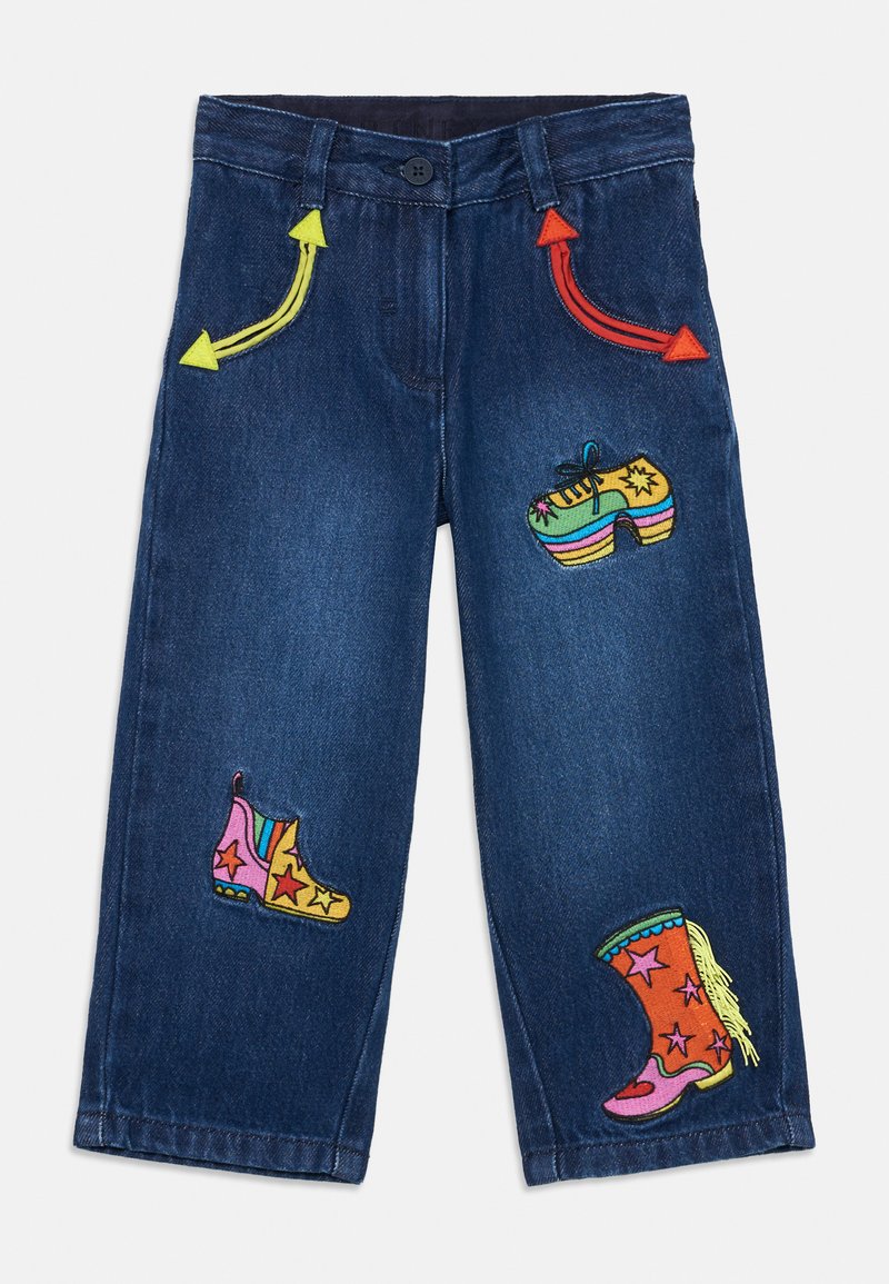 Τζιν από τζην με πολύχρωμες κεντήσεις: φωτεινές κίτρινες και κόκκινες βέλη, πολύχρωμες μπότες και μοτίβα αστεριών στο μπροστινό μέρος.