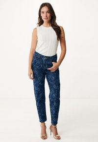 Jean en denim à motif floral bleu avec une coupe décontractée, dotés d'une taille haute et de poches avant, associés à un haut sans manches à côtes blanc.
