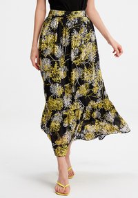 Jupe maxi florale noire avec des motifs de fleurs jaunes et blanches, fabriquée en tissu léger, dotée d'un ourlet volanté et d'une ceinture à la taille.