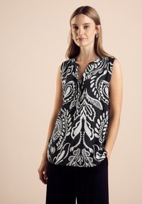Top senza maniche in bianco e nero con scollo a V, caratterizzato da un motivo floreale e una sottile texture. Vestibilità morbida con un dettaglio a tasca.
