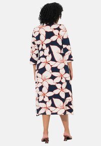 Abito con sfondo blu navy e grandi fiori bianchi e corallo. Maniche a tre quarti e vestibilità comoda, realizzato in tessuto morbido.