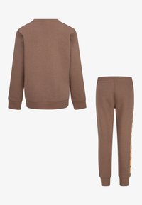 Ruda sportinė palaidinė ir derančios kelnės. Palaidinė su ilgomis rankovėmis, apvaliu iškirpimu. Kelnės siaurėjančios, su elastinga juosmens juosta ir spausdintu raštu.