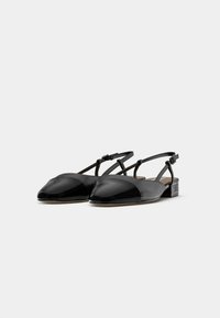 Fekete lakkbőr slingback lapos cipő hegyes orral, vékony bokapánttal és alacsony blokk sarokkal. Simább textúra fényes részletekkel.