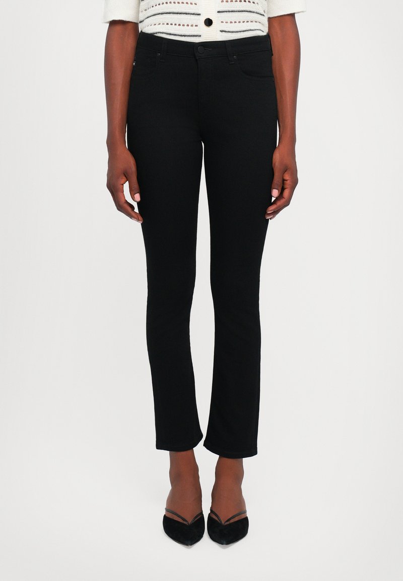 Black jeans with a slim fit design, made of smooth denim. Features classic pockets and a clean waistband. Styled with black heels.