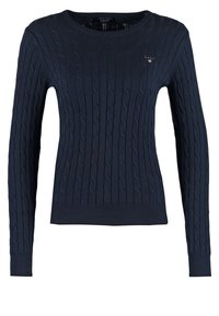 Pull en maille bleu marine avec motif torsadé, col rond, manches longues, et poignets et ourlet côtelés. Dispose d'un petit logo sur la poitrine.