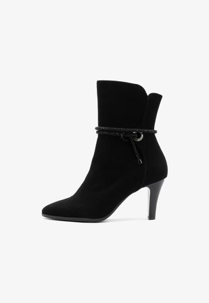 Czarne zamszowe botki za kostkę z ostrym noskiem, zwężanym obcasem oraz dekoracyjnym czarnym sznurkiem wokół cholewki z metalowym akcentem w kolorze srebrnym.