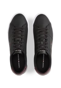 Schwarze Ledersneaker mit weißen Gummisohlen, dunklen Schnürsenkeln, Logo auf der Zunge und kastanienbraunen Akzenten an der Ferse. Glatte Textur.