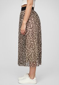 Midi sukně s leopardím potiskem vyrobená z průhledné tkaniny s elastickým černým pasem. Nošena s bílými sportovními botami, které ukazují hladký a plynulý střih.