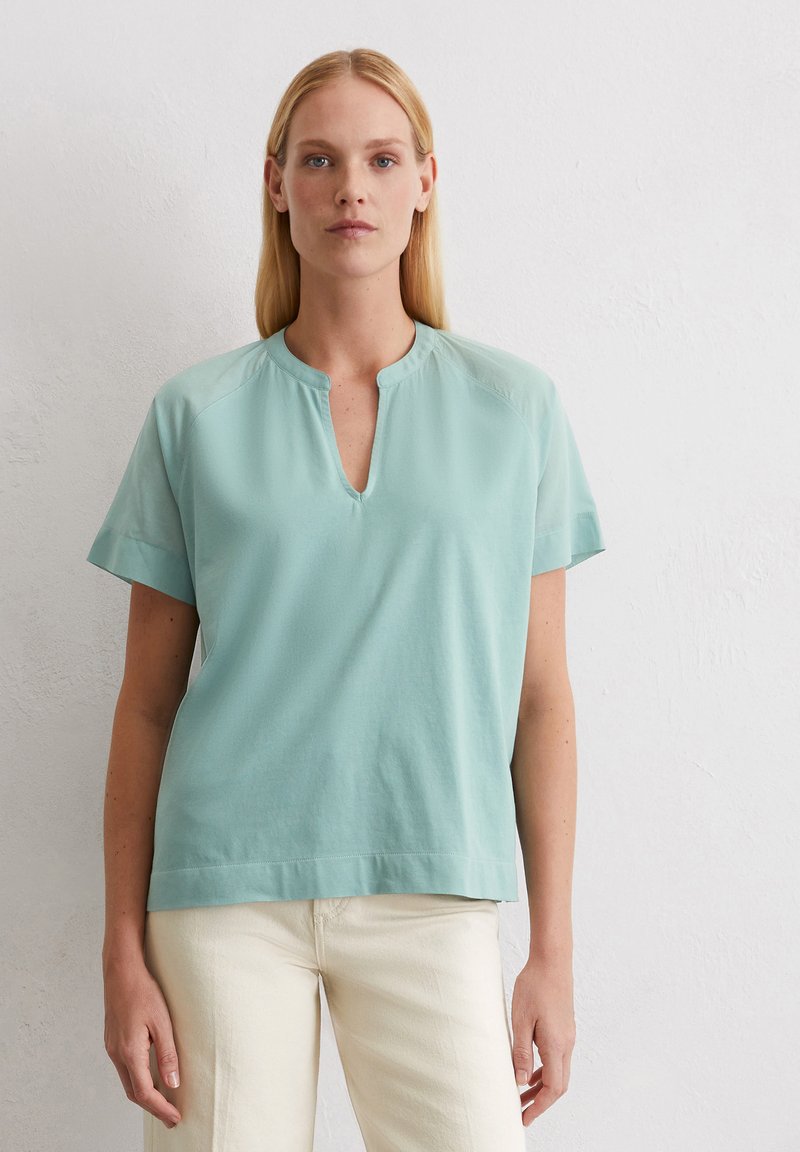 Blusa azzurro chiaro a maniche corte con scollatura rotonda e design minimalista, realizzata in tessuto morbido con una texture liscia.