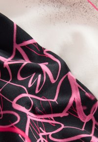 Cotton fabric featuring a black base with intricate pink abstract patterns. Smooth texture with a slight sheen, layered with cream-colored fabric.