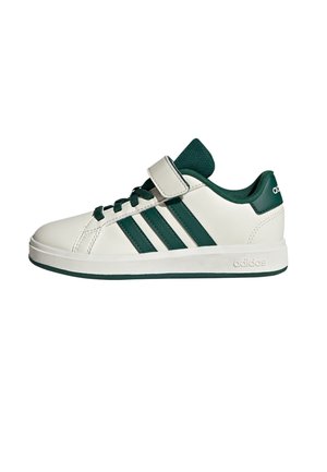 Baskets Adidas blanches à tige basse avec des rayures vertes, des lacets verts, une doublure intérieure verte et une seule sangle Velcro blanche sur un fond blanc.