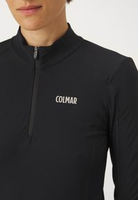 Fekete, hosszú ujjú felső negyed cipzárral. Simasága mellett a mellkasán feltűnő fehér "COLMAR" logó található.