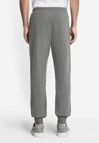 Grå bomullsträningsbyxor med avslappnad passform, ribbade muddkanter och elastisk midja, med en mjuk textur och utan synliga mönster.