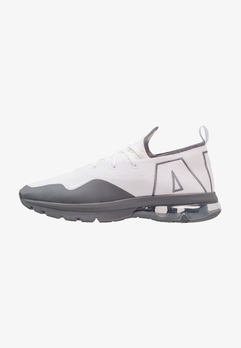 Chaussure de sport blanche et grise avec semelle à coussin d'air visible, design bas, languette de traction au talon et grand texte stylisé "AIR" sur le côté.