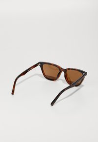 Skilpaddeskall solbriller med brune linser. Kattøyeform, glanset finish, slanke armer og subtil merking på den indre rammen.