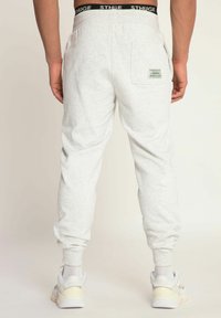 Lichtgrijze joggers gemaakt van zachte stof, met een zwarte merkband, elastische boorden en een achterzak met logodetail.