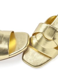 Gold sandals with a square toe, featuring wide cross straps and a smooth metallic texture. The design includes a layered accent on the straps.