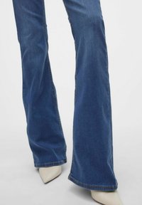 Uppklippta blå denimjeans med en mjuk textur, som har en klassisk femficksdesign och en något urtvättad finish. Matchas med spetsiga vita klackar.