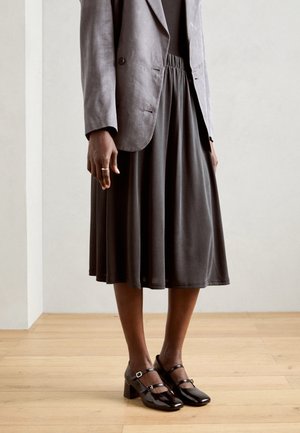 Gray linen blazer over a black elastic waist midi skirt, paired with black patent Mary Jane heels featuring a buckle detail.