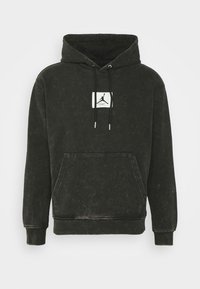 Felpa nera lavata con tasca a marsupio anteriore e lacci neri, presenta un'etichetta rettangolare bianca con un logo in silhouette.