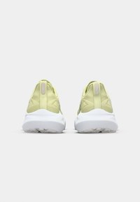 Des chaussures de sport vert lime avec une tige texturée, un talon rond et une semelle blanche. Comprend un onglet arrière lisse et une semelle extérieure crantée pour l'adhérence.