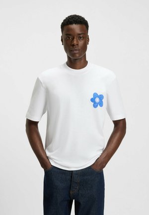 White cotton t-shirt with short sleeves, featuring a blue flower graphic with a smiley face on the left chest. Casual fit design.