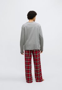 Gray long-sleeve shirt paired with red and black plaid pajama pants, featuring a relaxed fit and soft cotton texture.