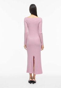 Ilgas rankoves, rausvos spalvos ribbingo mezginio suknelė su iškirpte nugaroje. Turi platų iškirptę ir prigludusią siluetą. Lygus tekstūra.