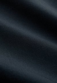 Tissu sombre à texture lisse avec un motif côtelé subtil, exhibant des nuances variées de noir. Excellent pour les vêtements ou le rembourrage.