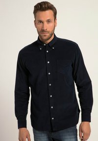 Camisa de botones azul marino en tela suave, con un bolsillo en el lado izquierdo del pecho, cuello estándar y cierres de botón blancos.