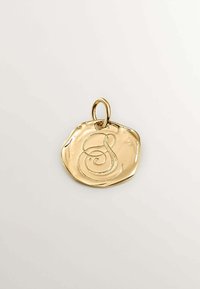 Colgante dorado con una forma irregular y texturizada. Presenta una "S" estilizada grabada en el centro y un aro para su sujeción.