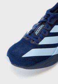Granatowy but do biegania z jasnoniebieskimi akcentami, cholewką z siateczki, smukłym designem i teksturowanym wykończeniem. Na boku znajduje się logo "ADIZERO".