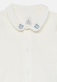 Polo shirt en coton blanc avec un col arrondi, des accents en broderie de ours bleu et une fermeture à bouton à l'avant. Taille 12 mois/74 cm.