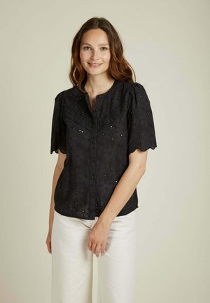Blouse noire à boutons avec des manches courtes bouffantes, ornée de broderies florales détaillées et de bords festonnés le long des manches et de l'ourlet.