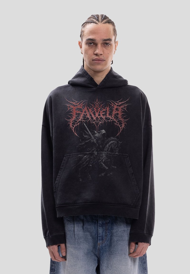 Jeune personne avec des tresses porte un sweat à capuche noir avec un texte rouge complexe et un graphisme d'un chevalier sombre à cheval, assorti d'un jean bleu délavé.