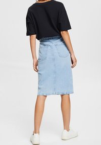 Vaaleansininen farkkuhame, joka on keskipitkä ja jossa on kaksi takataskua sekä hieman kulutettu helmaväri. Yhdistetty mustan lyhythihaisen t-paidan kanssa.