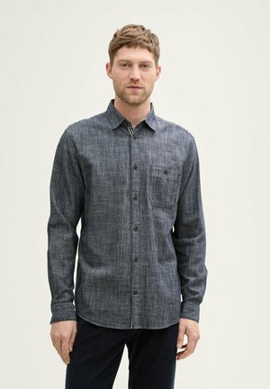 Dark blue denim shirt with long sleeves, button-up front, single chest pocket, and textured fabric pattern. Collar for structured look.