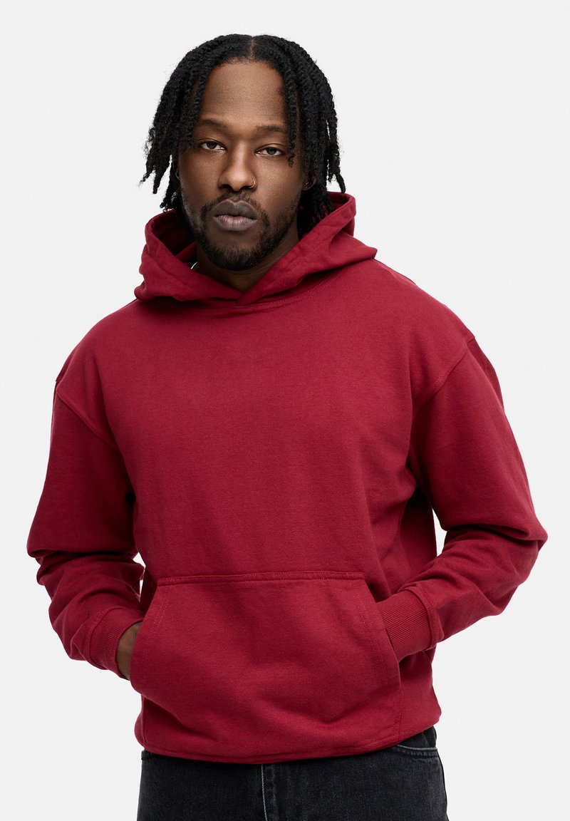 Roter Kapuzenpullover mit Kängurutasche, hergestellt aus einem Baumwollmischgewebe. Verfügt über eine lockere Passform und gerippte Bündchen.