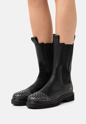 Zwarte leren enkellaarsjes met een getextureerde, met ronde studs versierde neuskap, elastische zijpanelen en aantreklussen voor gemakkelijk aan- en uitrekken.