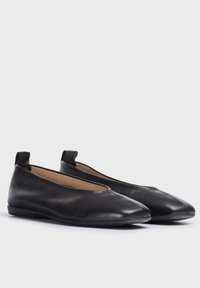 Bailarinas de cuero negro con textura suave, diseño de punta afilada y acentos elásticos para un fácil calzado. Ligeras y con estilo minimalista.
