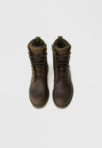 Botas de couro castanho de atacadores com um colarinho almofadado, sola resistente e um forro interior suave. Apresentam um logótipo na lateral e costuras duráveis.